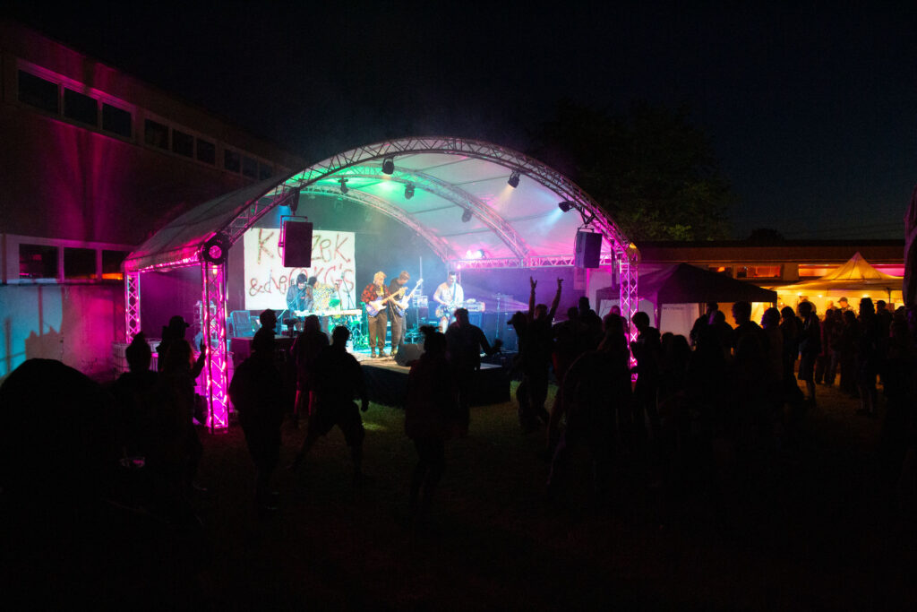 Band spielt abends auf der bunt beleuchteten Bühne vor tanzendem Publikum beim Göss OpenAir 2026 in Gössmannsreuth.