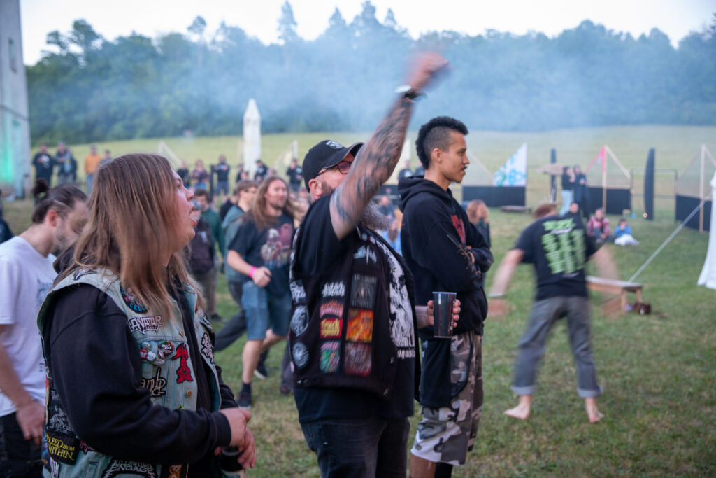 Publikum mit Patches und Kutten steht bei Dämmerung auf der Festivalwiese beim Göss OpenAir 2026 in Gössmannsreuth.