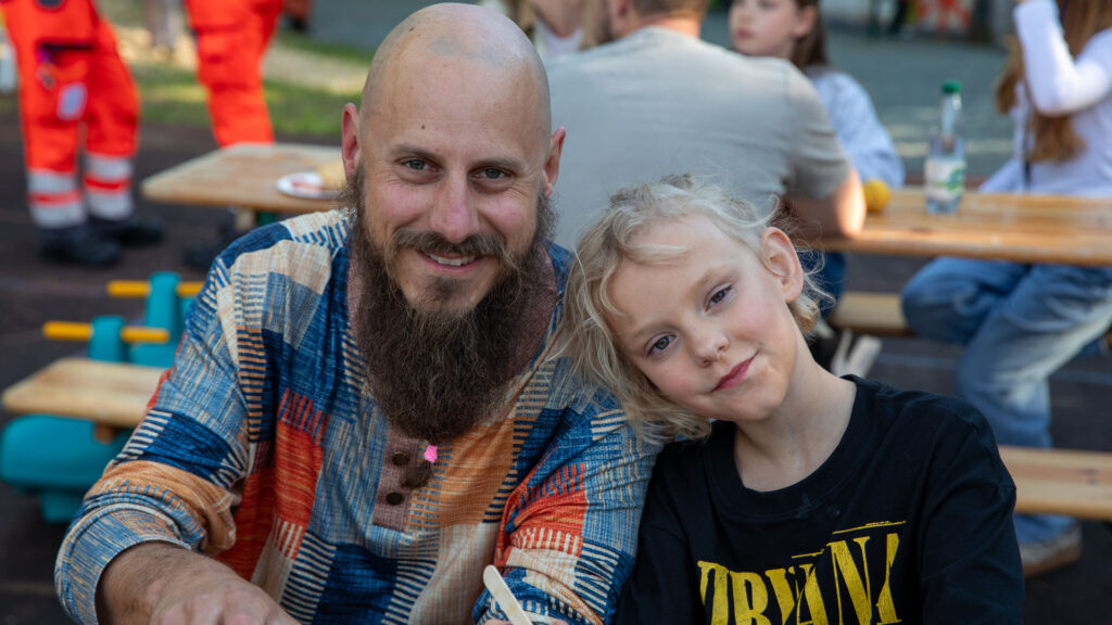 Ein Vater sitzt lachend mit seiner Tochter an den Bierbänken beim Göss OpenAir 2026 in Gössmannsreuth.